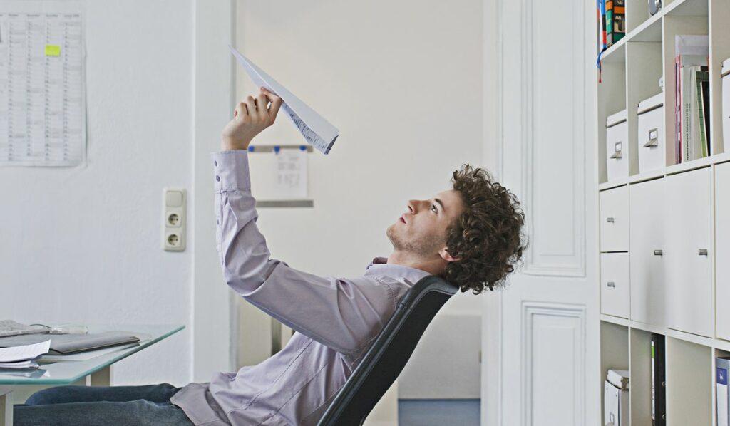 Quiet quitting : un employé lance un avion en papier au lieu de travailler.