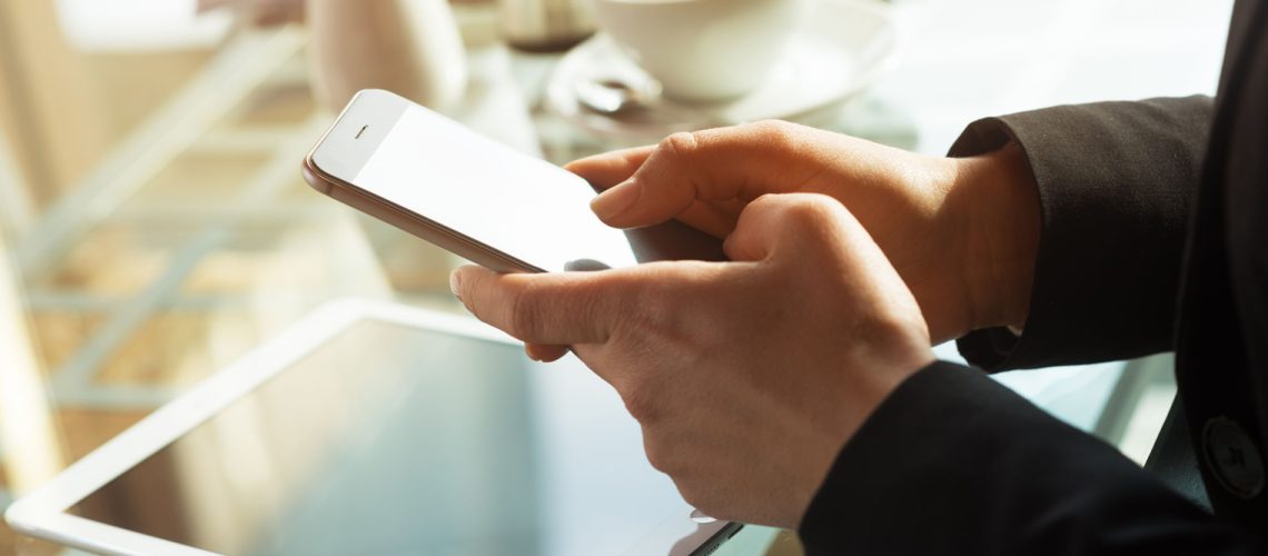 36869018 - businesswoman at the bar text messaging with her mobile touch screen phone, hands close up