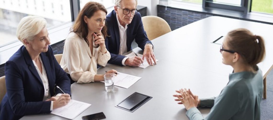 Woman during job interview and three elegant members of management